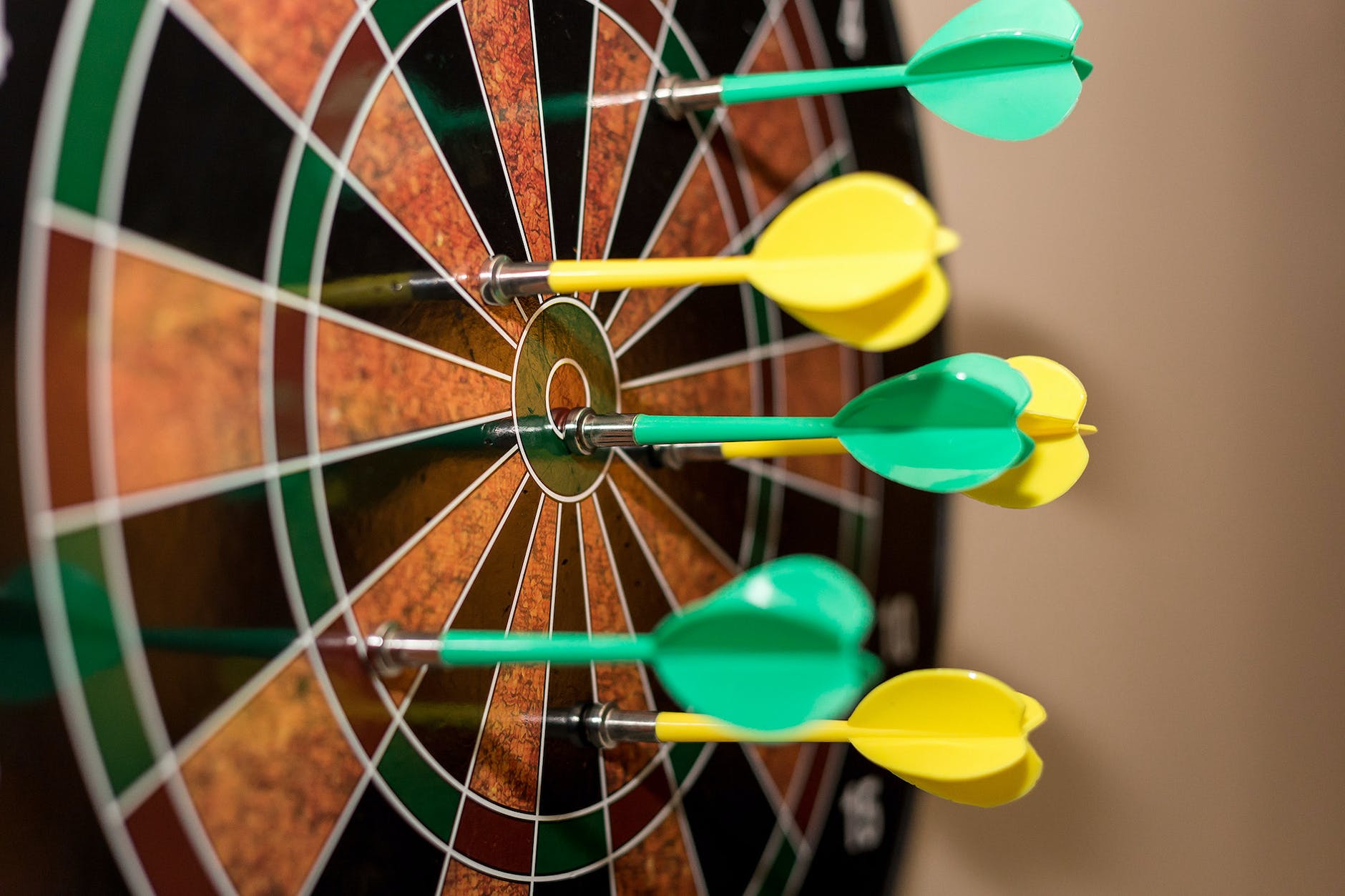 green and yellow darts on brown black green and red dartboard