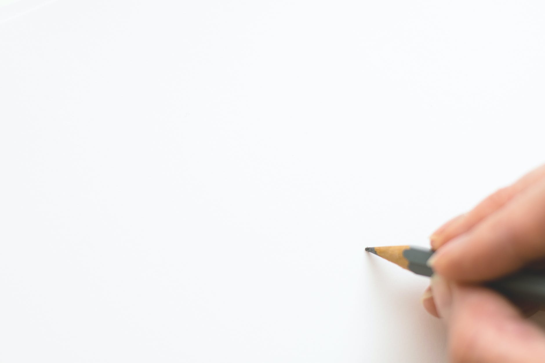 close up of hand holding pencil over white background