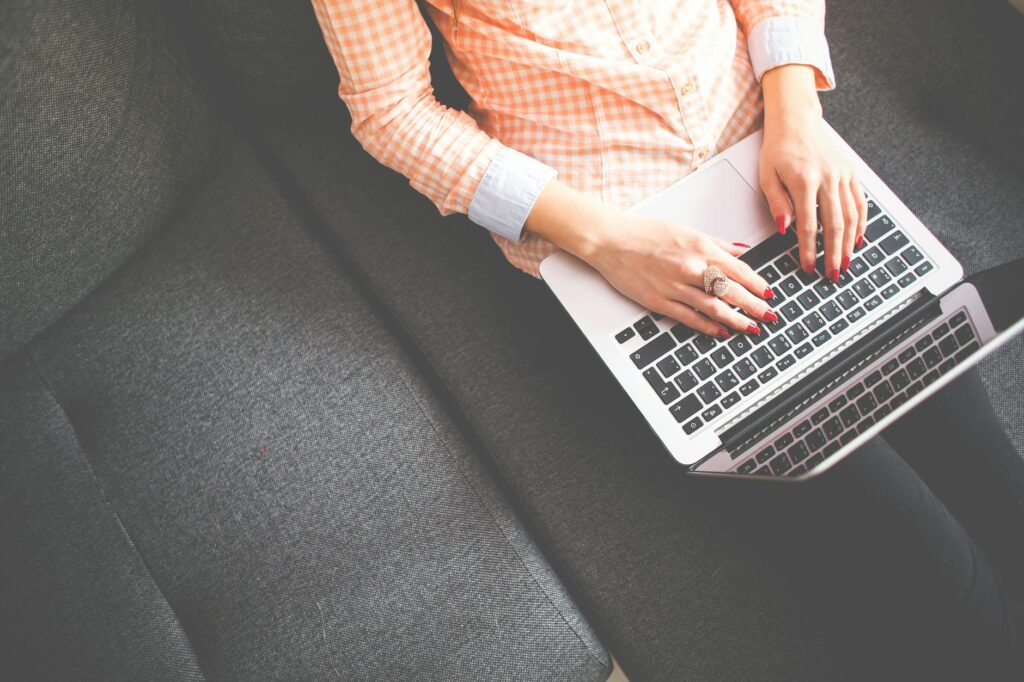 person sitting on gray sofa while using macbook